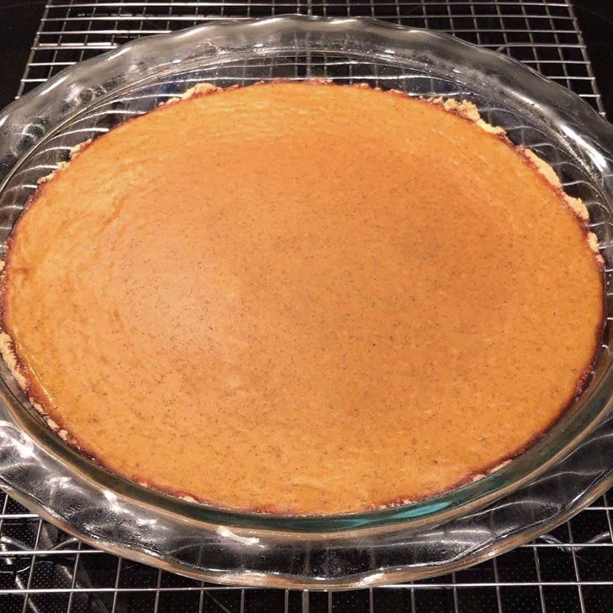 protein pumpkin pie in a glass pie dish on a cooling rack