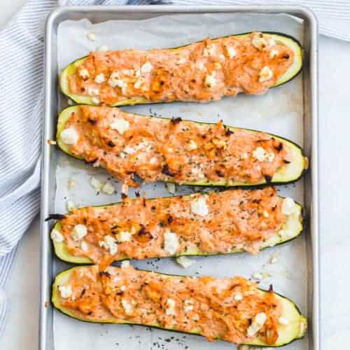 4 chicken filled zucchini halves on a baking pan