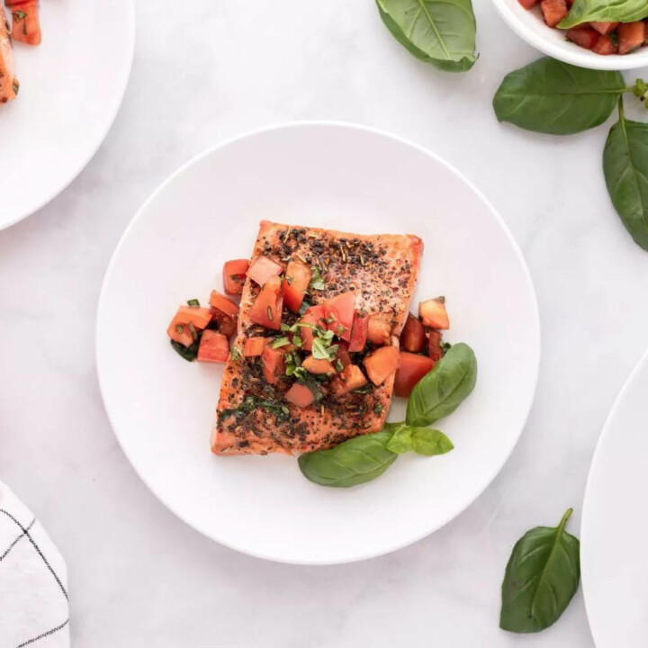 piece of salmon with tomatoes and basil