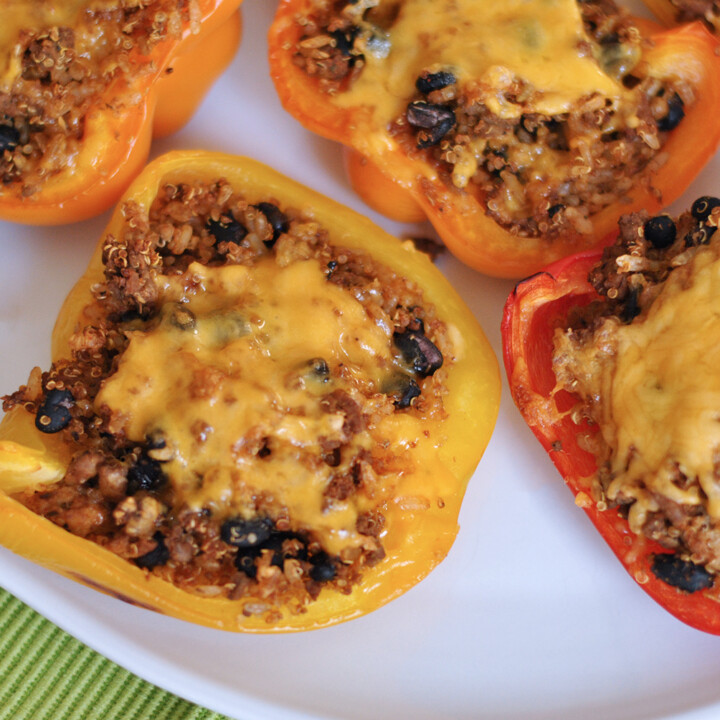 a plate of stuffed bell peppers filled with quinoa and black beans, and topped with cheddar cheese
