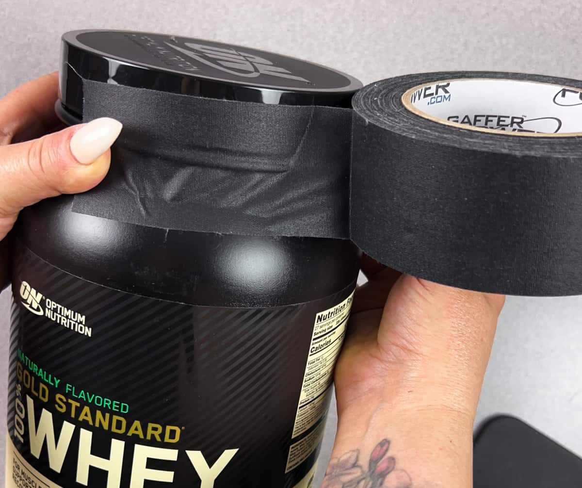 using gaffer tape to seal the top of a tub of protein powder for travel.