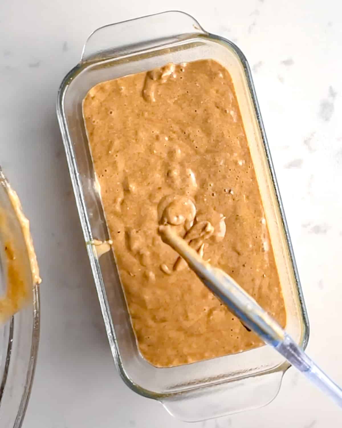 protein banana bread batter in a glass pyrex loaf pan.