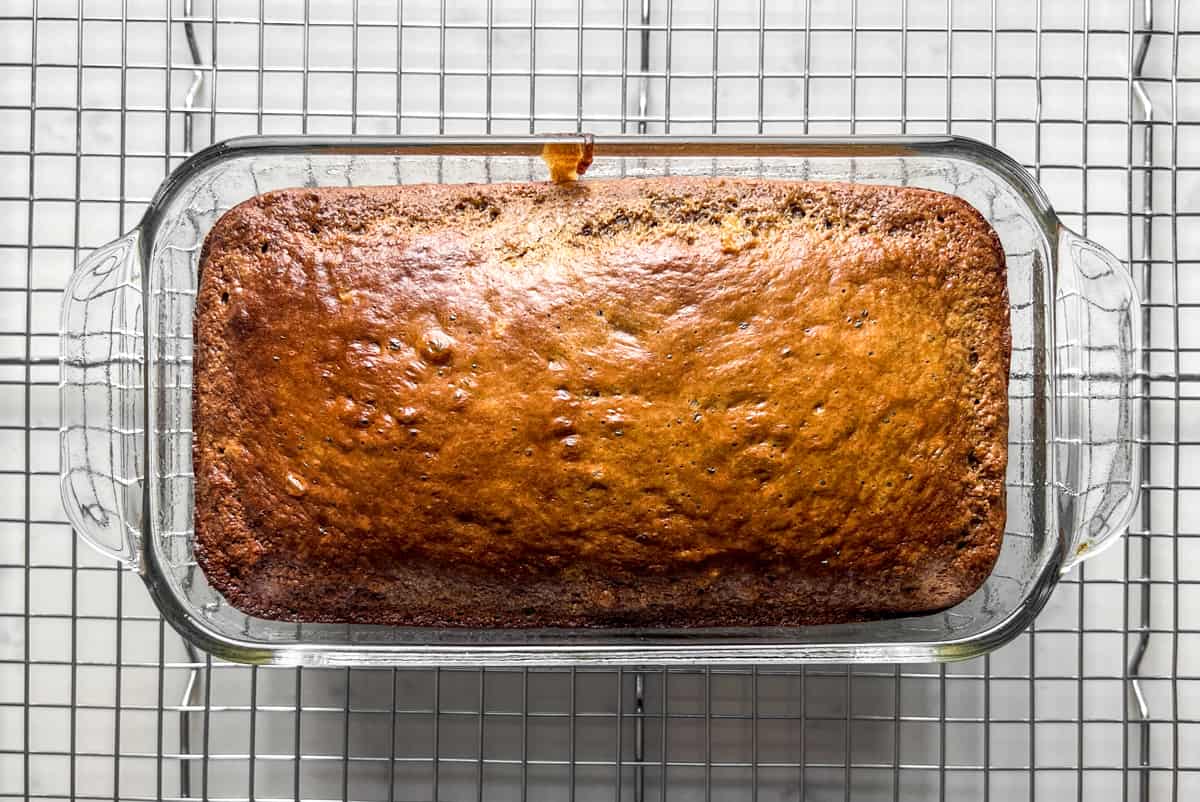 top view of a loaf of protein banana bread in a glass baking pan on a wire cooling rack.