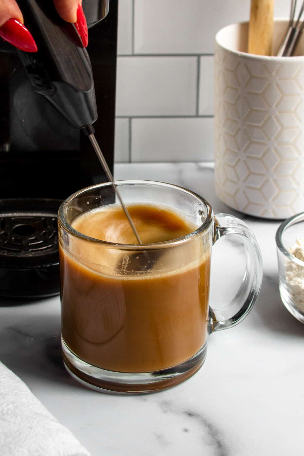 protein powder being mixed into hot coffee with a milk frother.