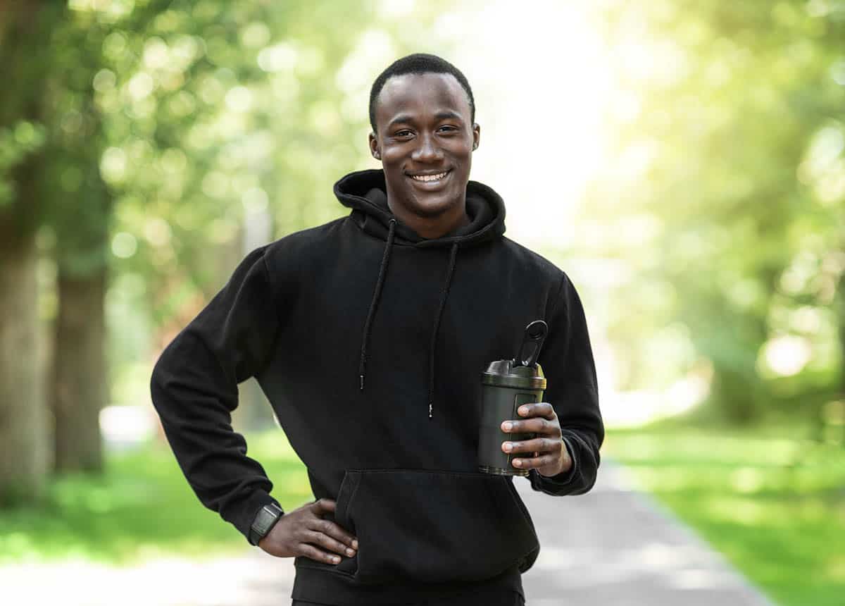 man in black sweatshirt holding a protein shake.