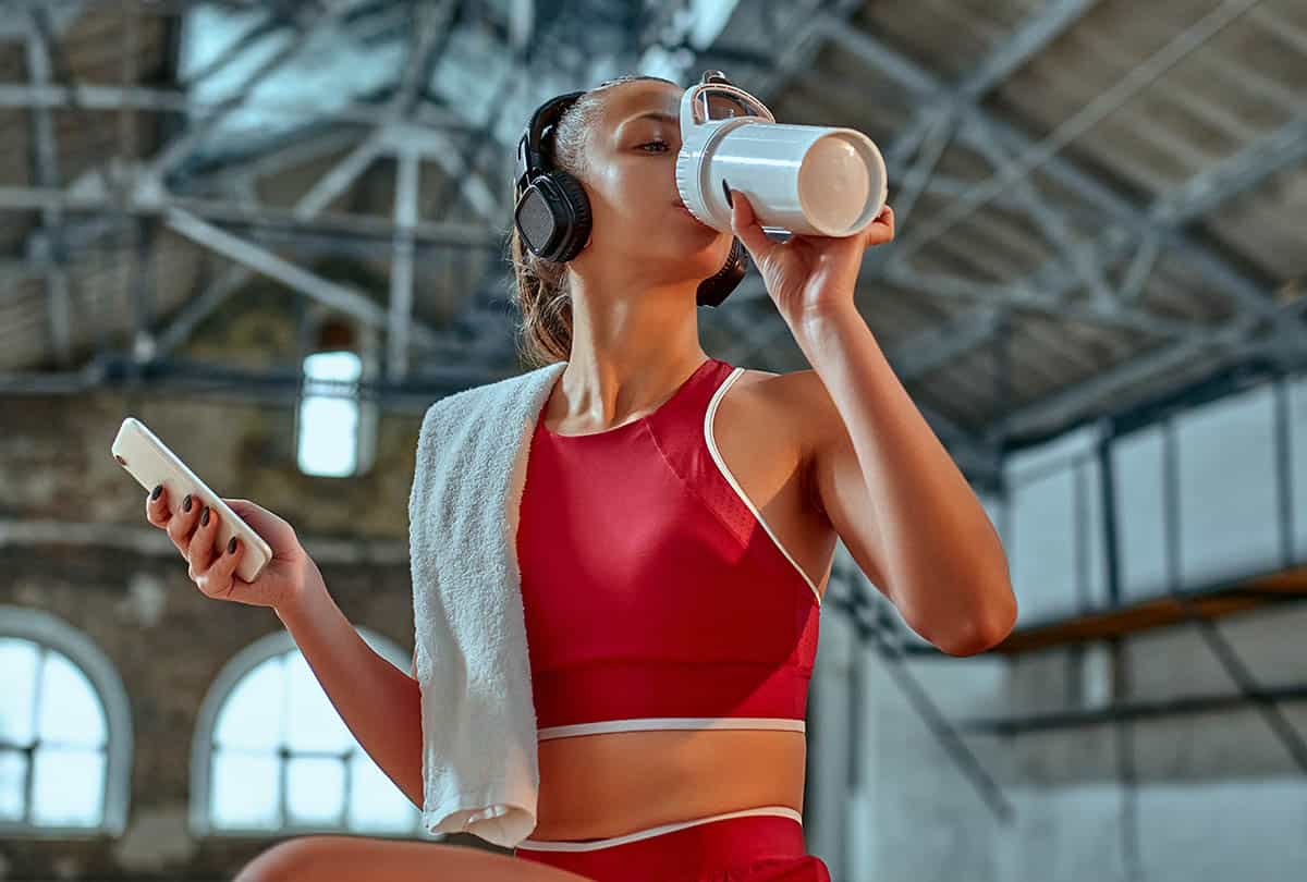 woman in red athletic gear drinking a protein shake.