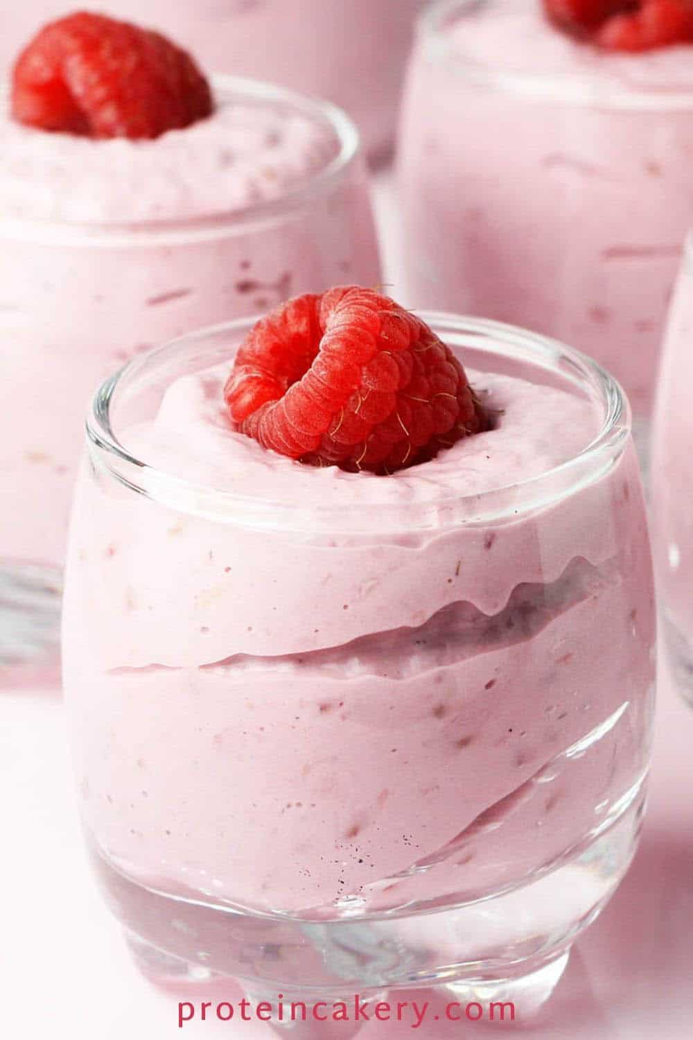 raspberry cheesecake mousse in shot glasses with a fresh raspberry on each