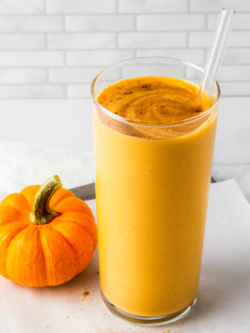 pumpkin protein shake next to a mini pumpkin