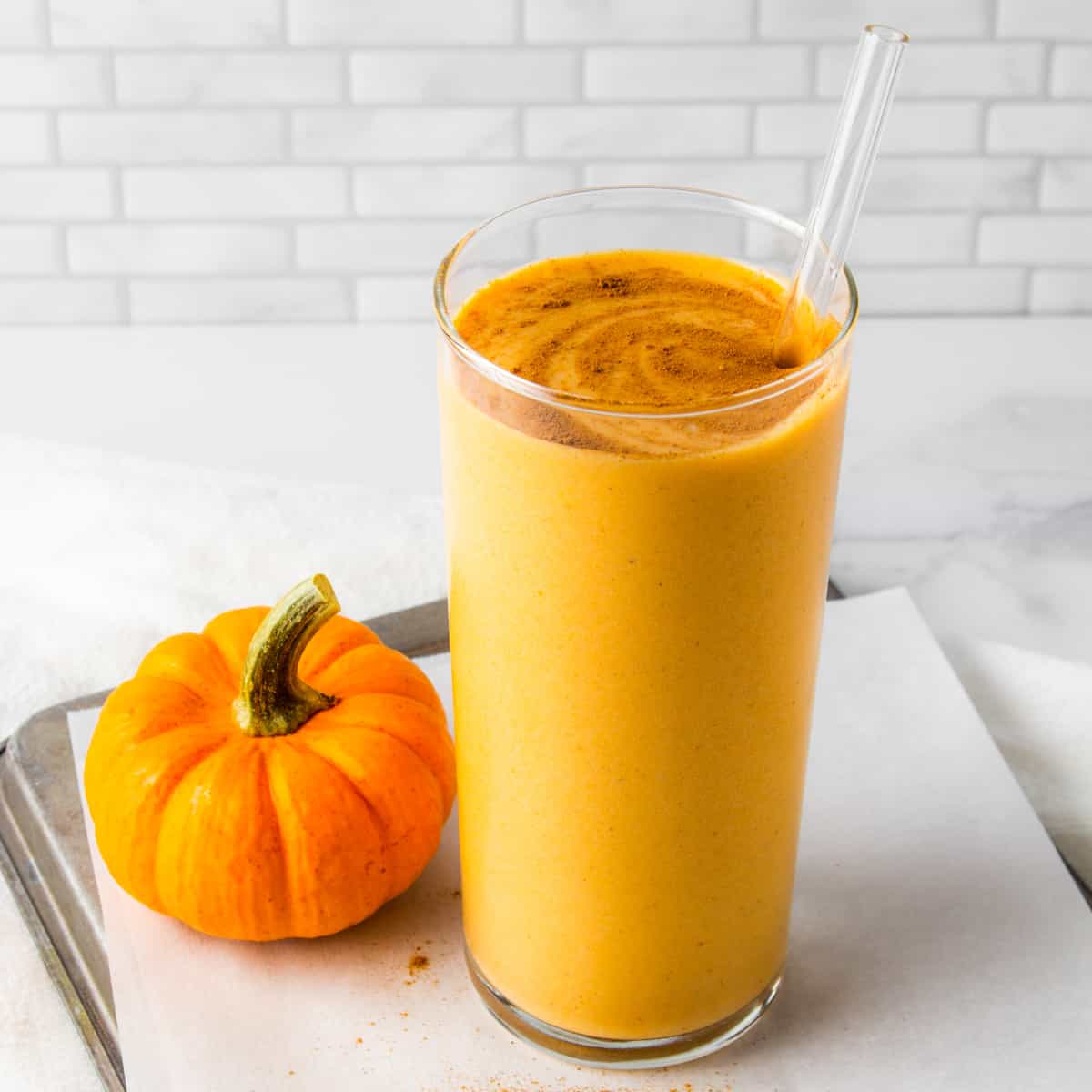 pumpkin protein shake next to a mini pumpkin