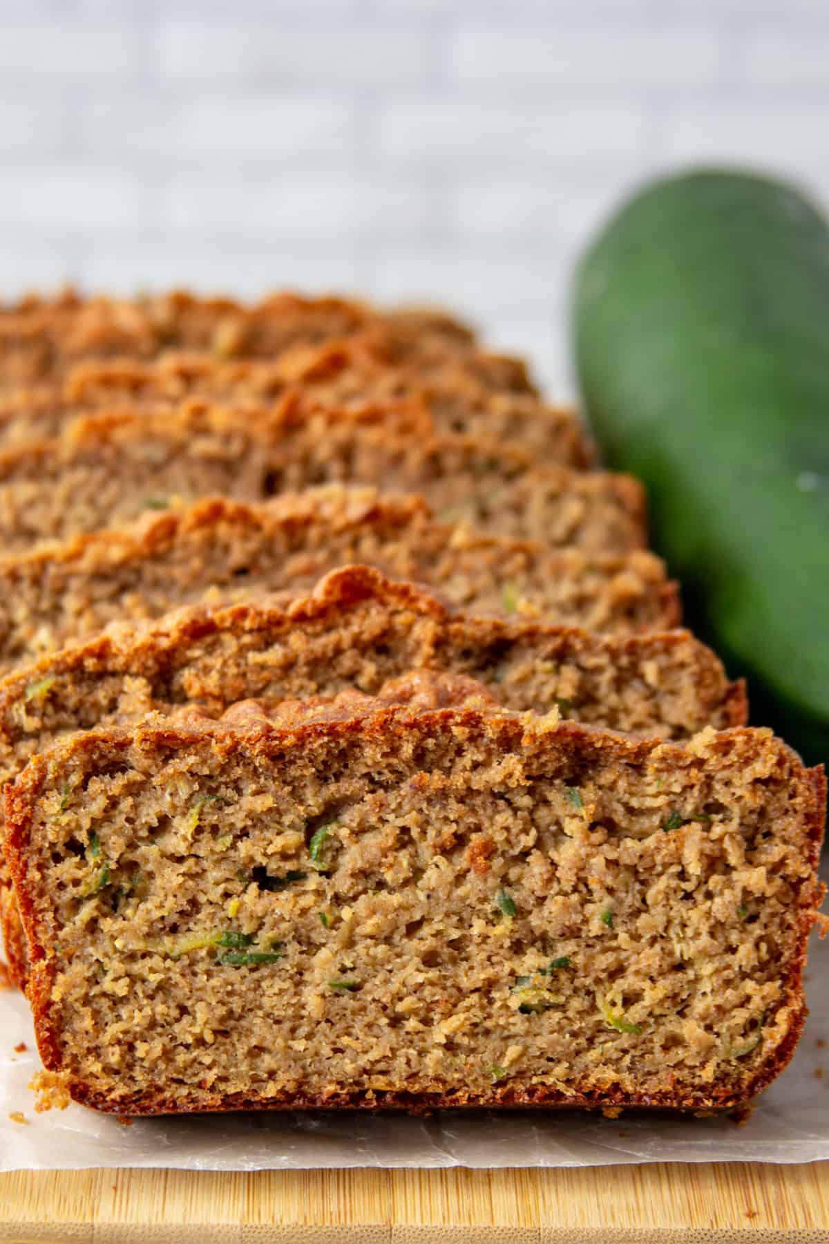 slices of high protein zucchini bread next to a zucchini.
