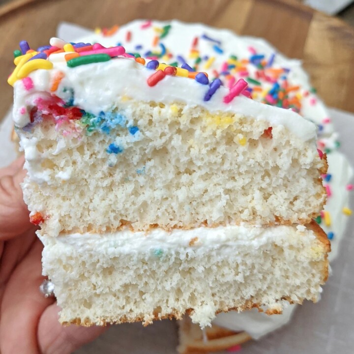 piece of layered protein birthday cake in a hand.