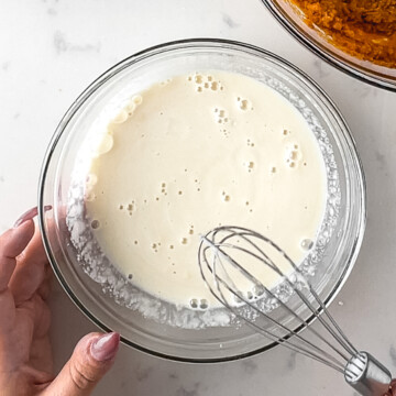 whey protein and water mixed together in a glass mixing bowl with a small whisk.
