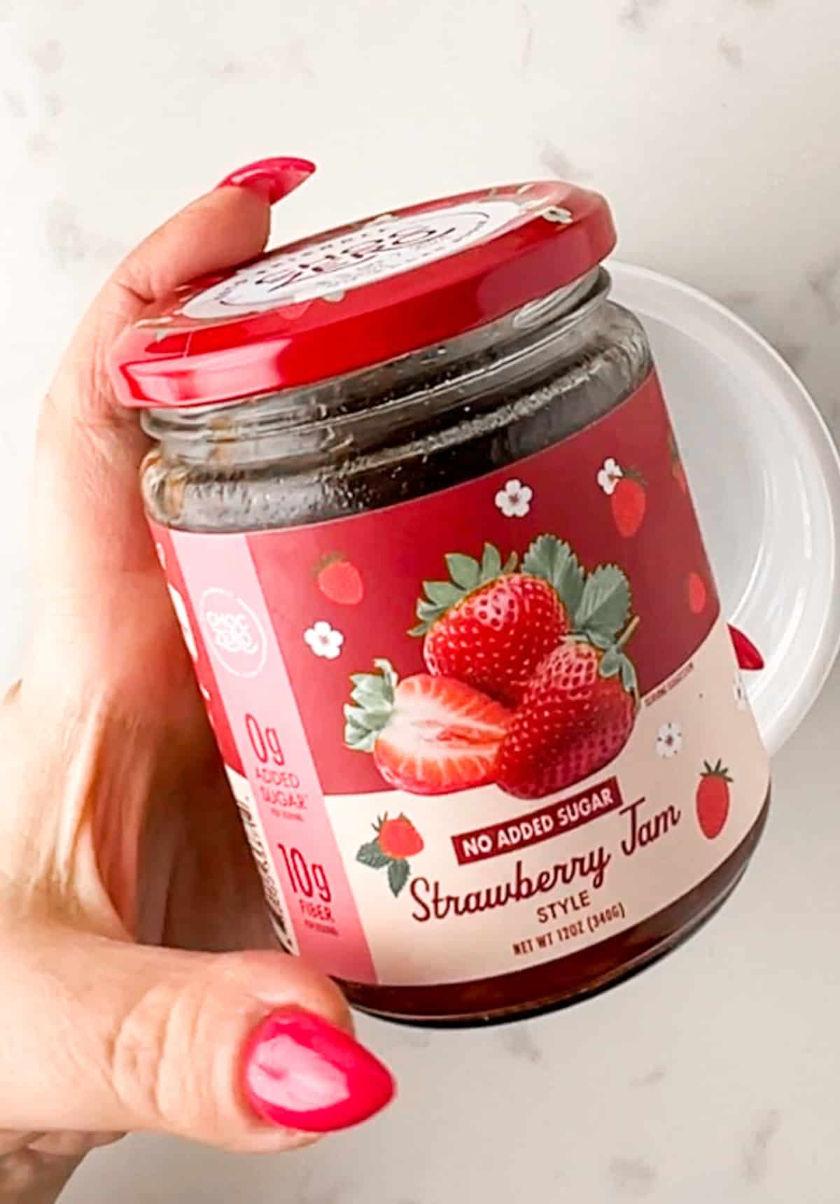 hand holding a jar of sugar free strawberry jam.