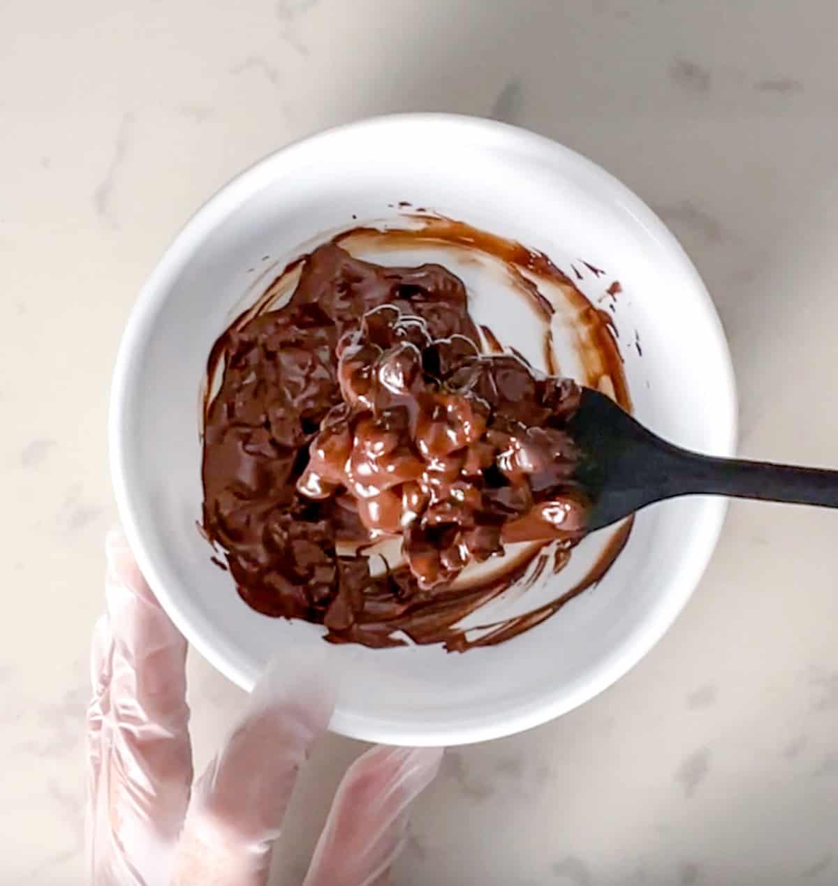 bowl of partially melted sugar free chocolate chips with a spatula.