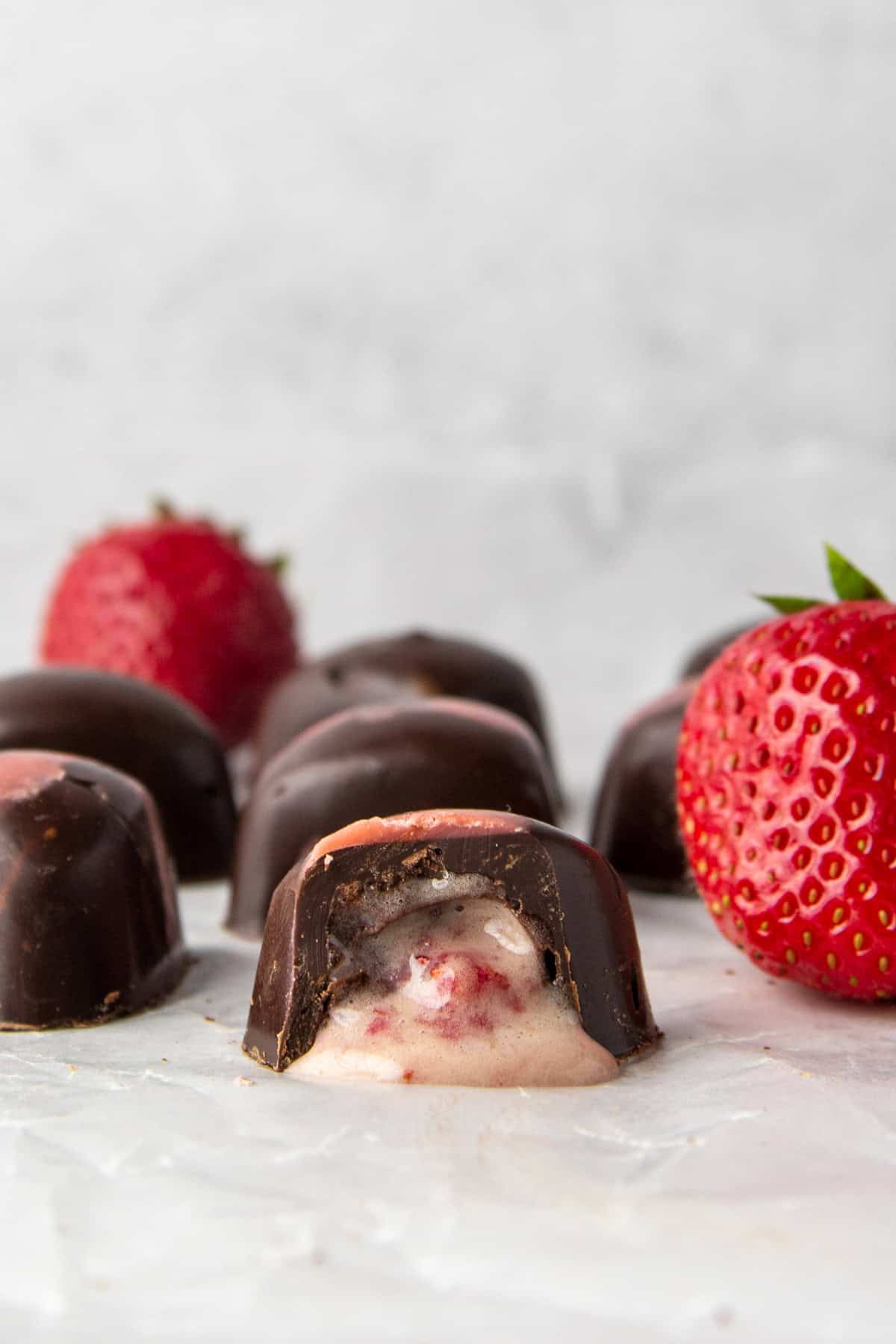 sugar free filled chocolates with strawberry high protein filling, shown with fresh strawberries.