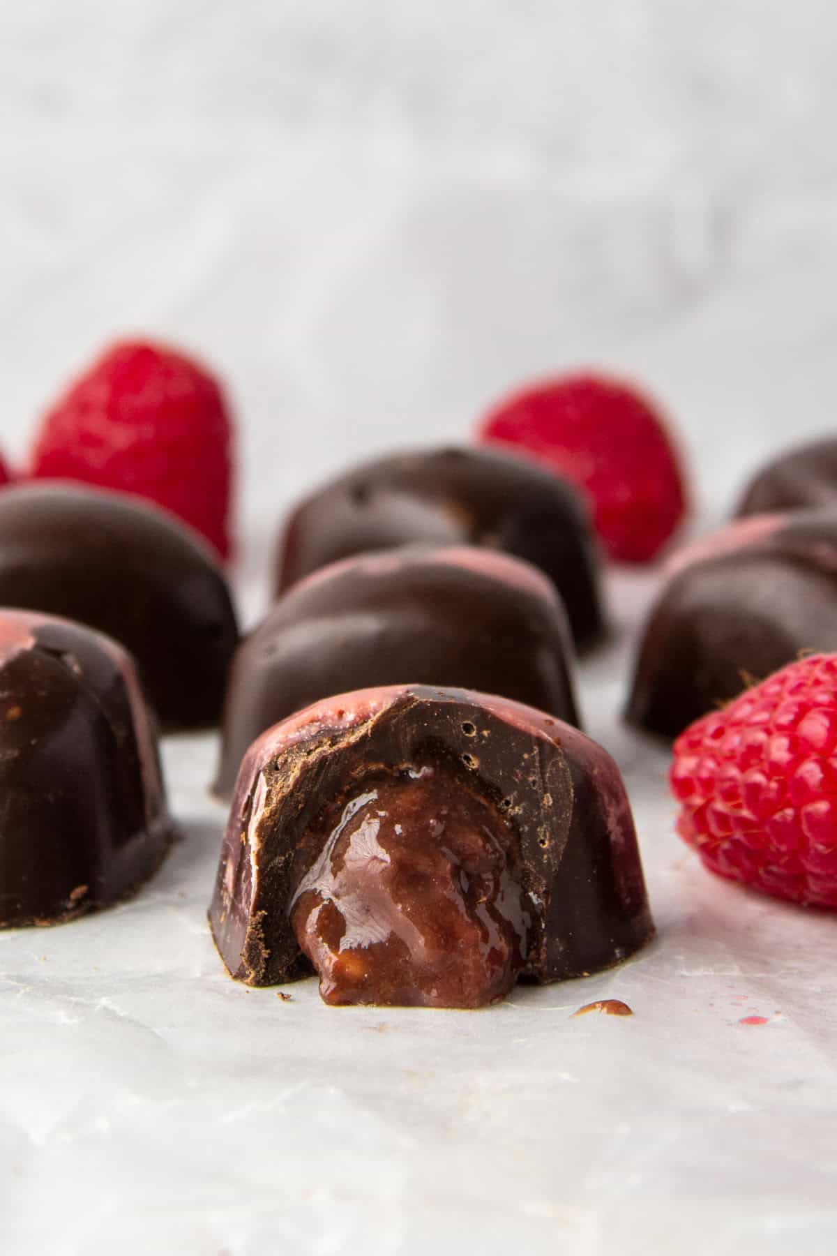 sugar free filled chocolates with chocolate raspberry high protein filling, shown with fresh raspberries.