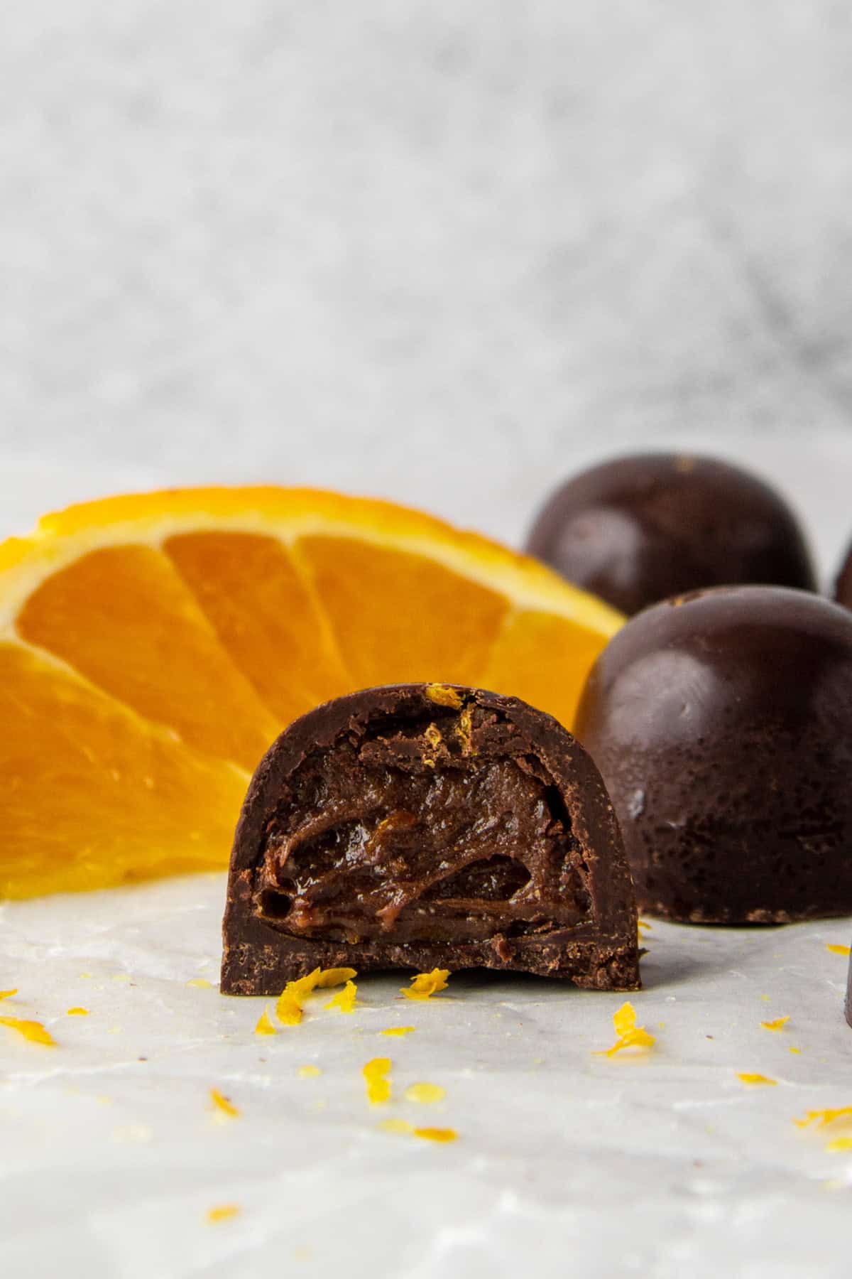 sugar free chocolates filled with a high protein chocolate orange whey protein filling, shown with orange zest and an orange slice.