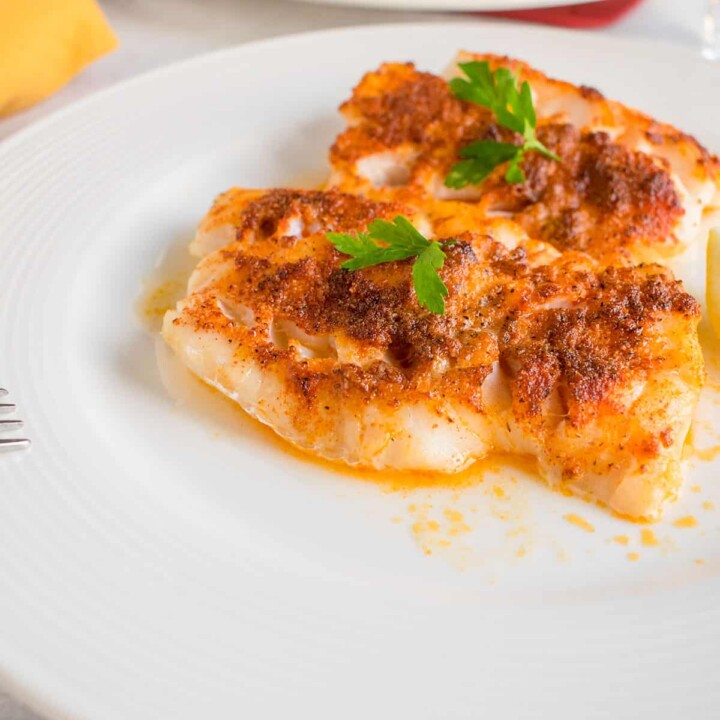 two pieces of broiled cod on a plate.