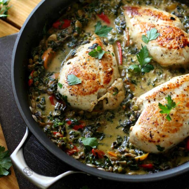 3 chicken breasts in a skillet with vegetables.