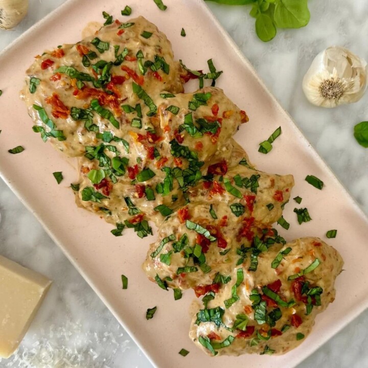 4 pieces of chicken breast on a plate with garnish.