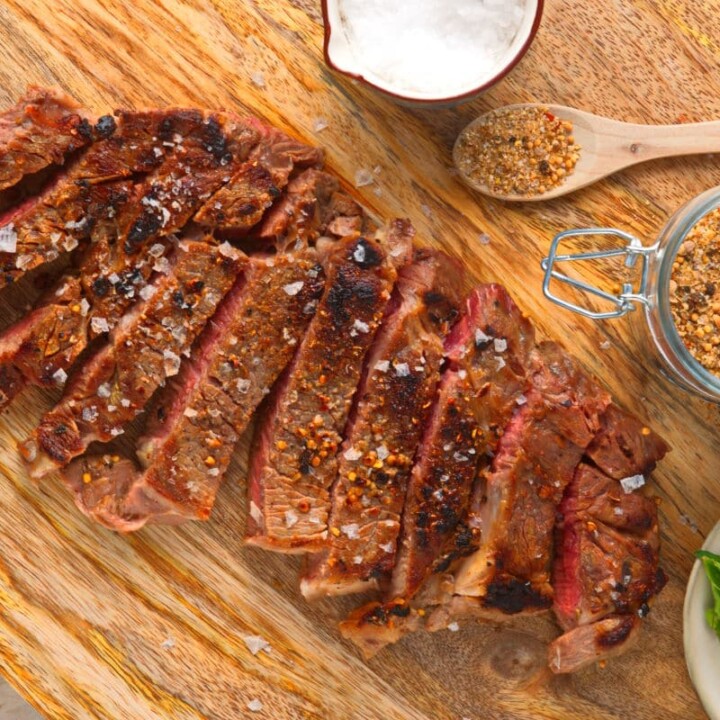 sliced bison rib eye on a cutting board.
