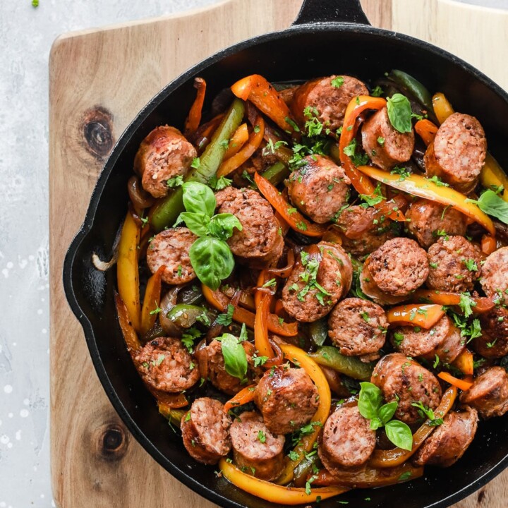 sliced pieces of sausage with onion of peppers in a skillet.