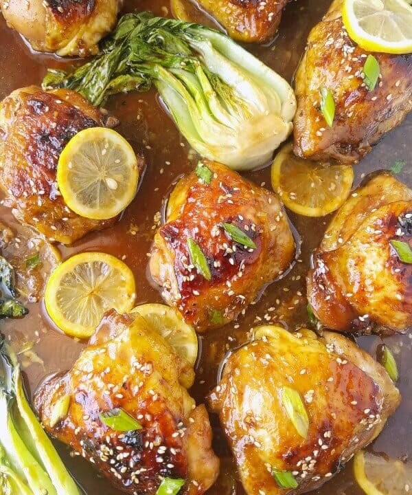 pan of honey chicken with bak choy and lemon slices.