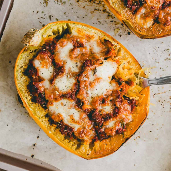 two halves of spaghetti squash stuffed with vegan meat and topped with cheese.
