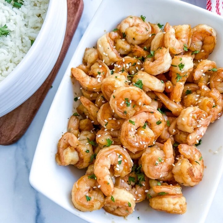 hibachi shrimp on a plate next to a bowl of rice.