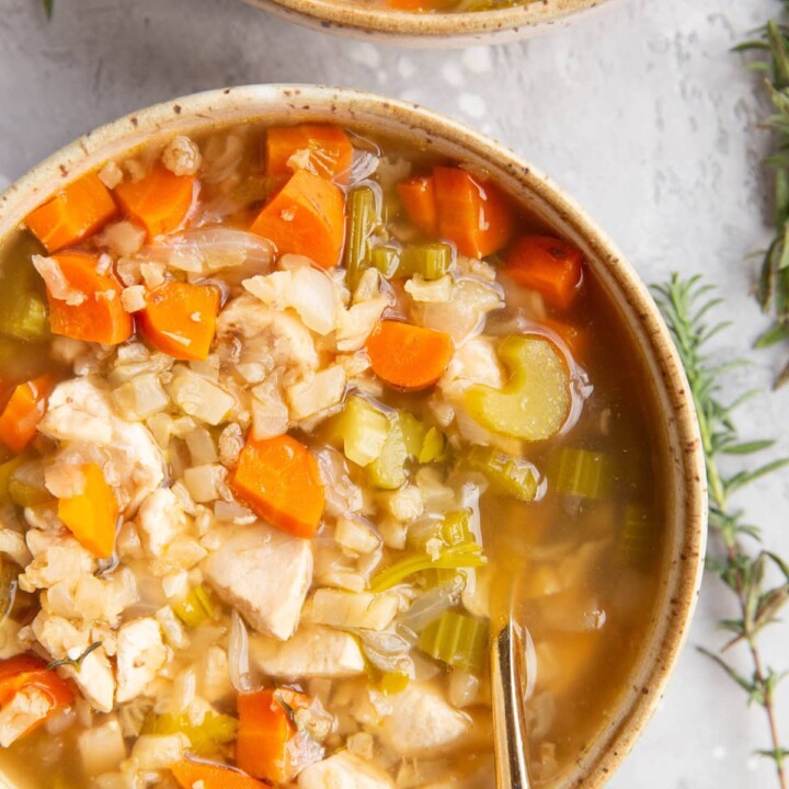 two bowls of chicken cauliflower soup with carrots.