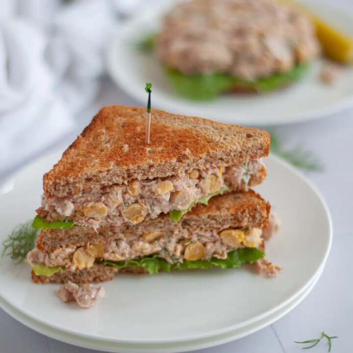 tuna salad sandwich cut in half on a plate.