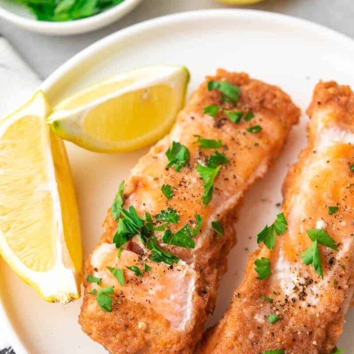 two pieces of salmon with lemon wedges.
