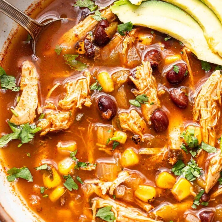 bowl of chicken tortilla soup with sliced avocado.