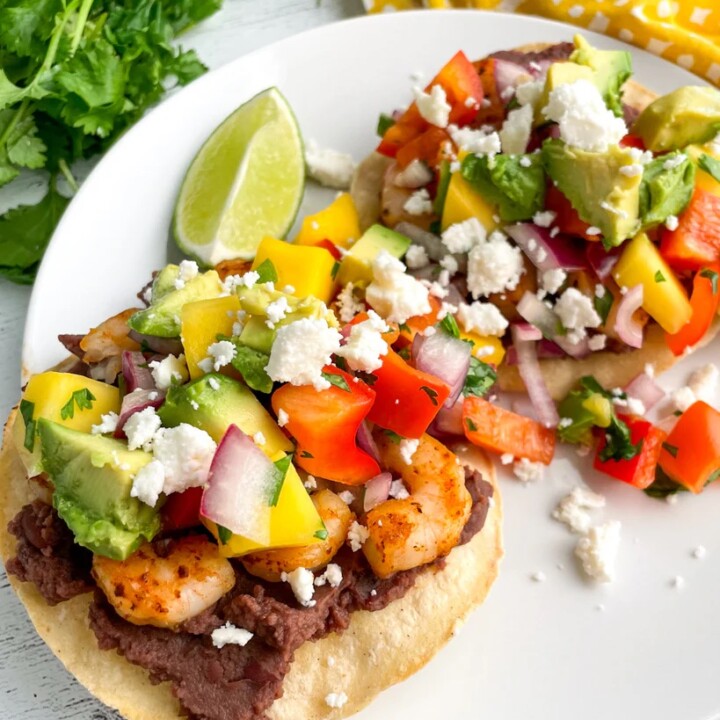 Mango avocado shrimp tostadas plated with a lime wedge.
