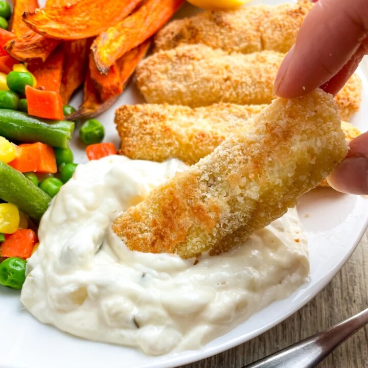healthy fish stick being dipped into tartar sauce.