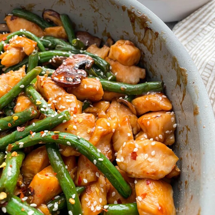 a bowl of gluten free chicken and string bean stir fry with sesame seeds.