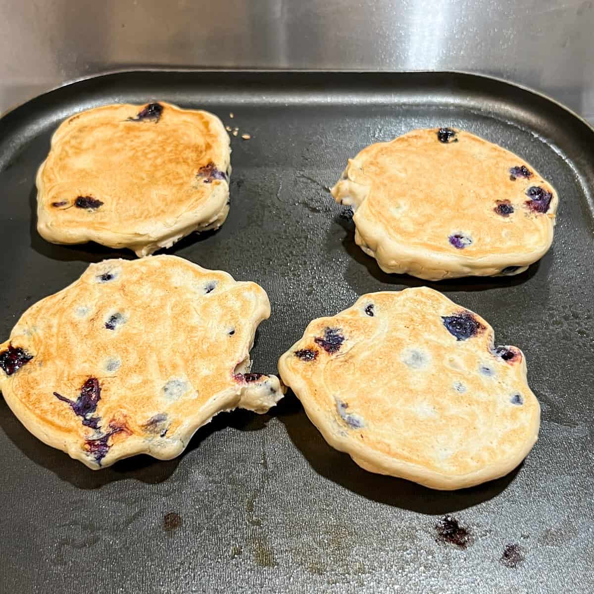 blueberry protein pancakes on a griddle ready to eat.