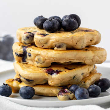 stack of gluten free blueberry protein pancakes with fresh blueberries.