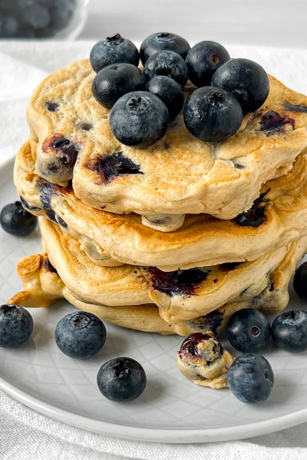 stack of high protein blueberry pancakes with fresh blueberries.