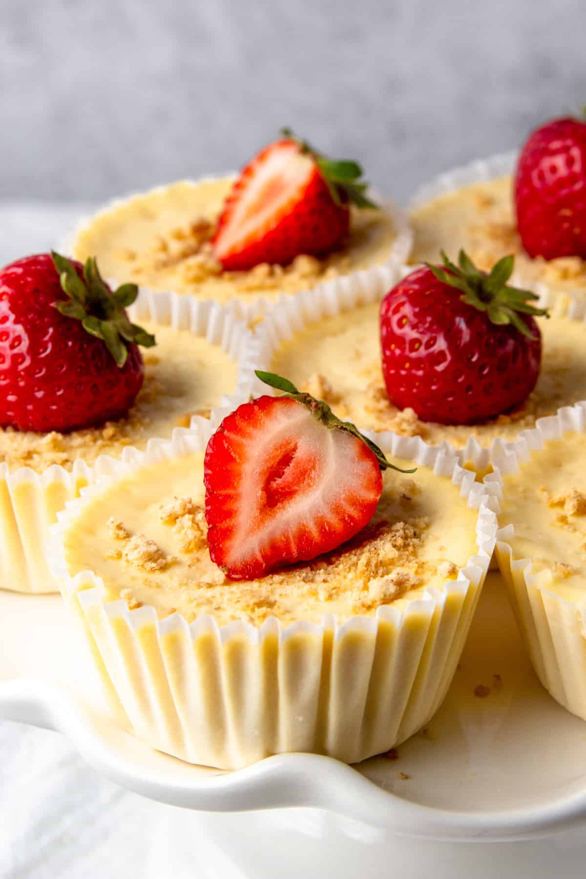 mini protein cheesecakes topped with strawberries and graham cracker crumbs.