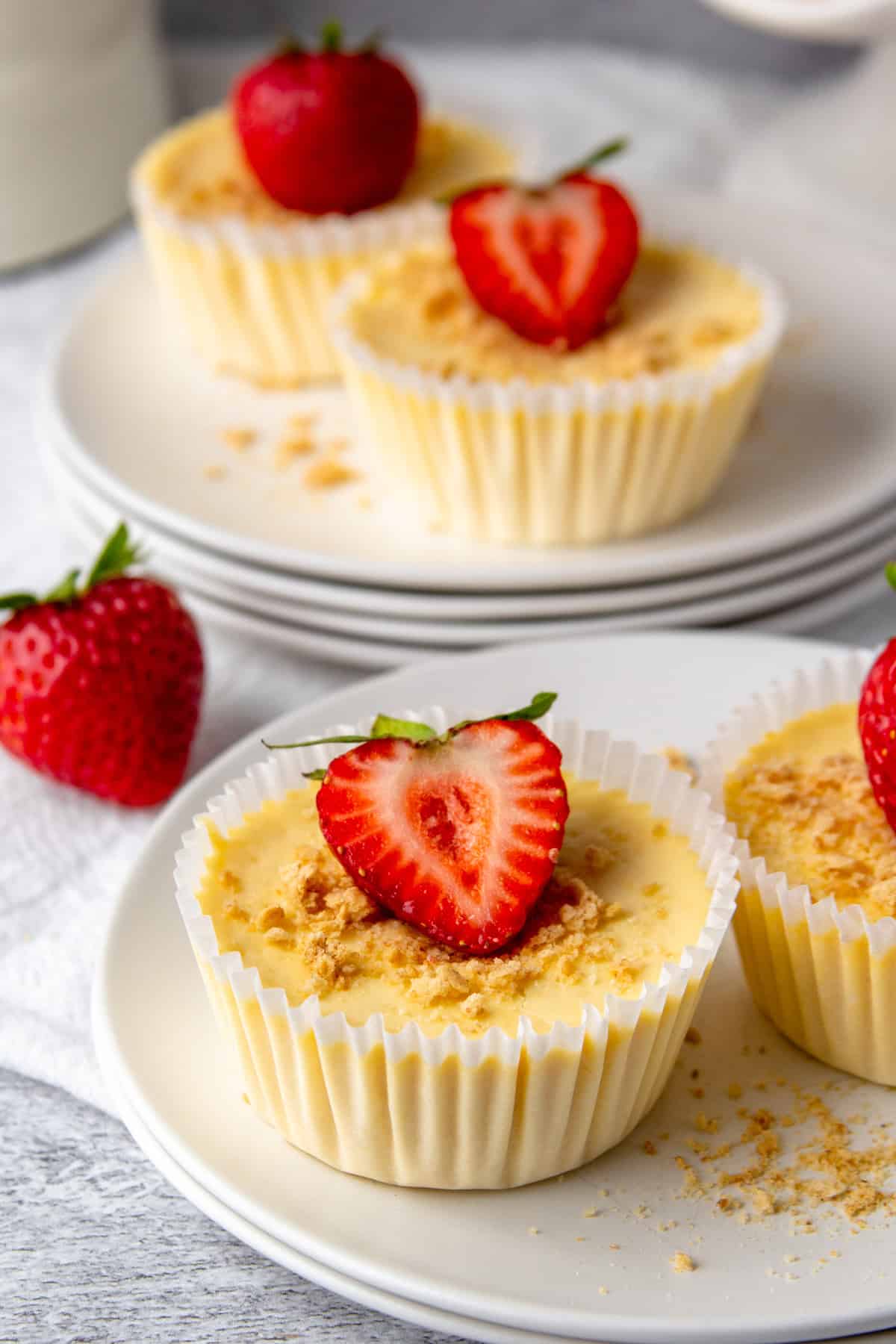 mini protein cheesecakes topped with strawberries and graham cracker crumbs.