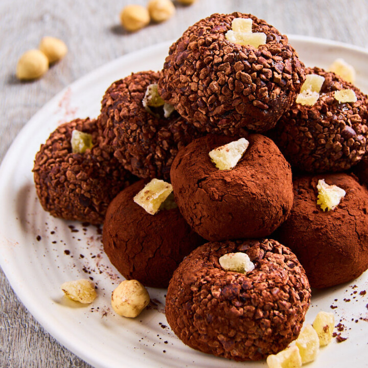 chocolate ginger protein balls piled on a white plate.