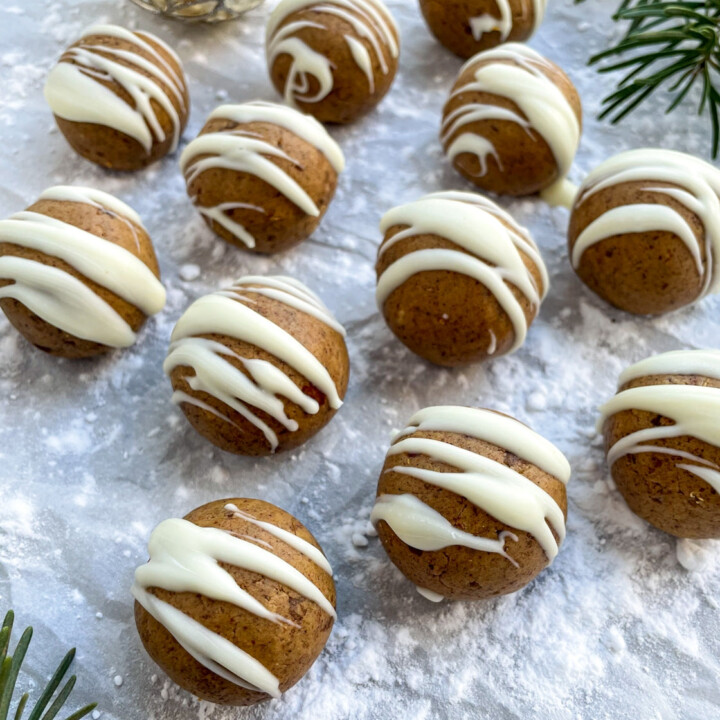 gingerbread protein balls drizzled with white chocolate surrounded by christmas decor.