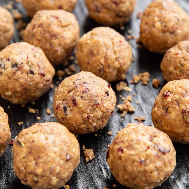 cranberry almond protein balls on a black surface with crumbs.