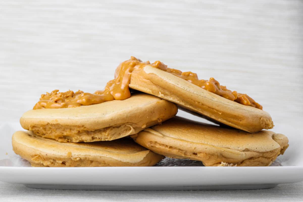 stack of fluffy peanut butter protein pancakes with peanut butter on top.