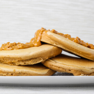 stack of fluffy peanut butter protein pancakes with peanut butter on top.