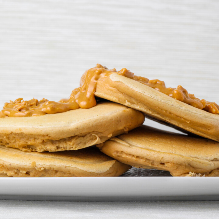 stack of fluffy peanut butter protein pancakes with peanut butter on top.