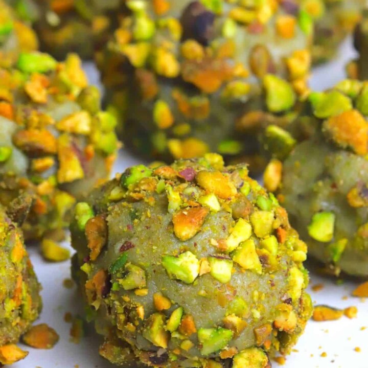pistachio protein balls coated in crushed pistachios on a plate.