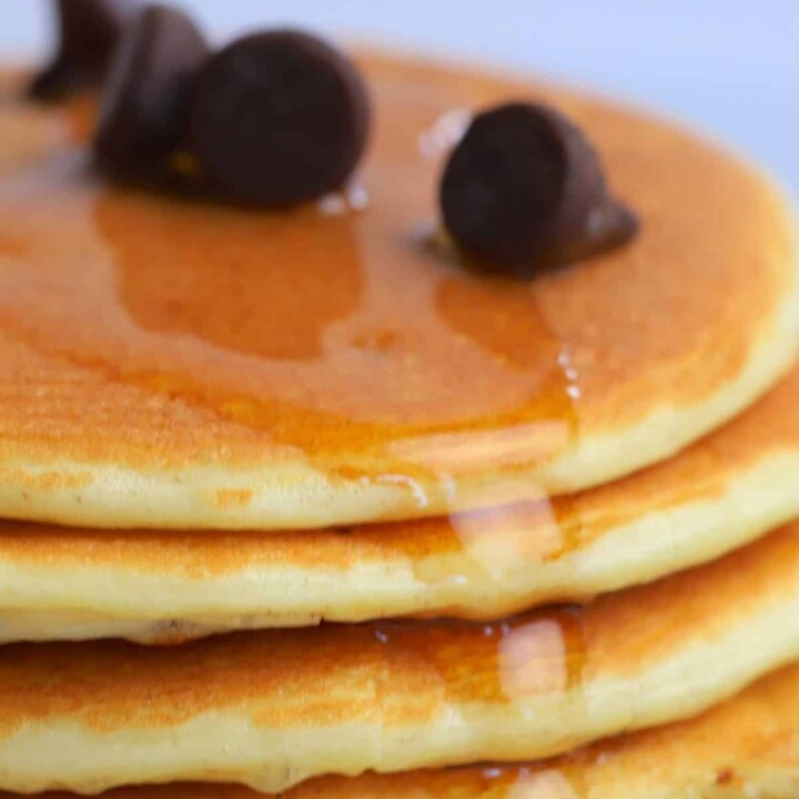 closeup of a stack of protein pancakes topped with chocolate chips.