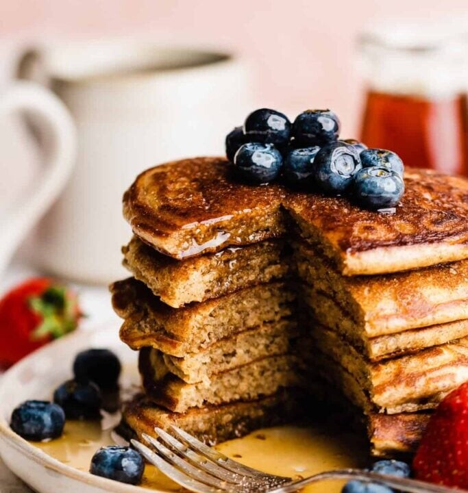 cut stack of protein pancakes topped with blueberries.